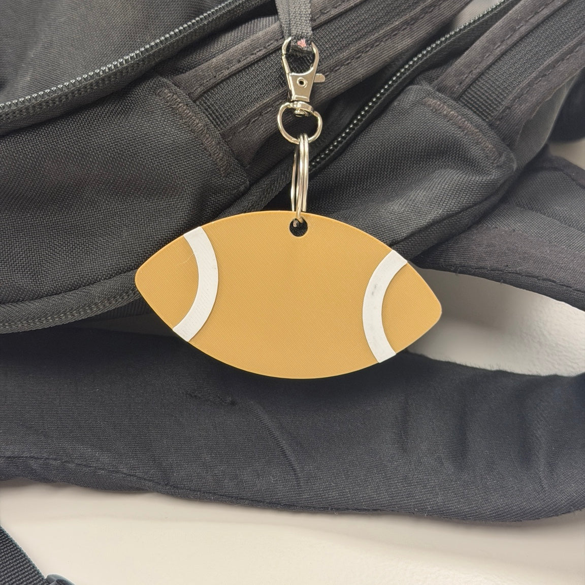 Gold football-shaped keychain attached to a black bag