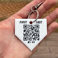Hand holding a keychain with a QR code and customizable text on a blurred background