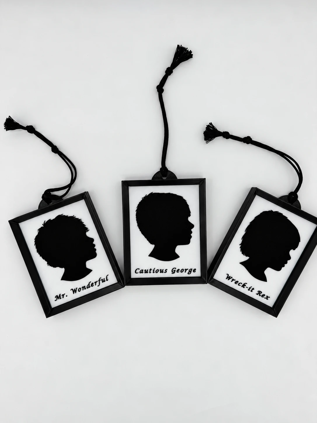 Three personalized black-frame silhouette ornaments made by 4Life